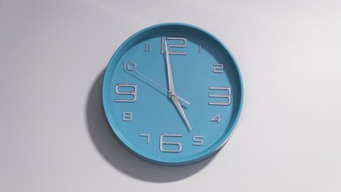 Timelapse of a blue clock on a white wall. The clock starts ticking at 5 and ends at 12. Stock Video