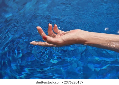 Hand of unrecognizable female tourist swimming in clean pool water during summer vacation in tropical hotel Stock Photo